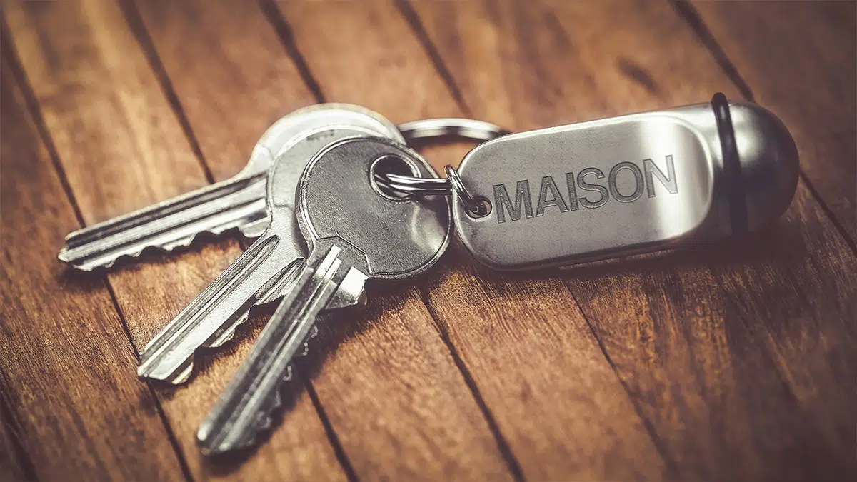  Photo d'une clé avec un porte-clé en métal marqué "MAISON", symbolisant la réception d'une maison